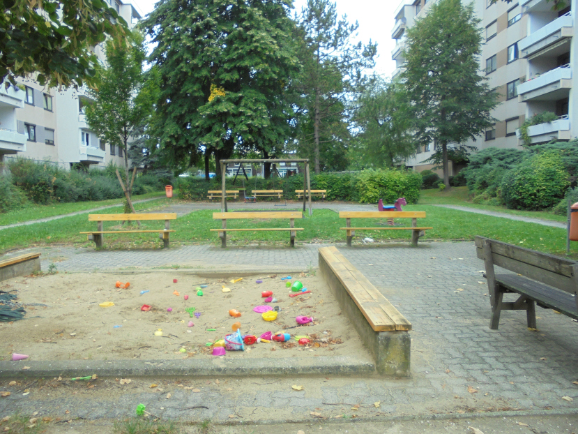 Spielplatz mit Sandkasten, Schaukel und Bänken in Wohnhausanlage