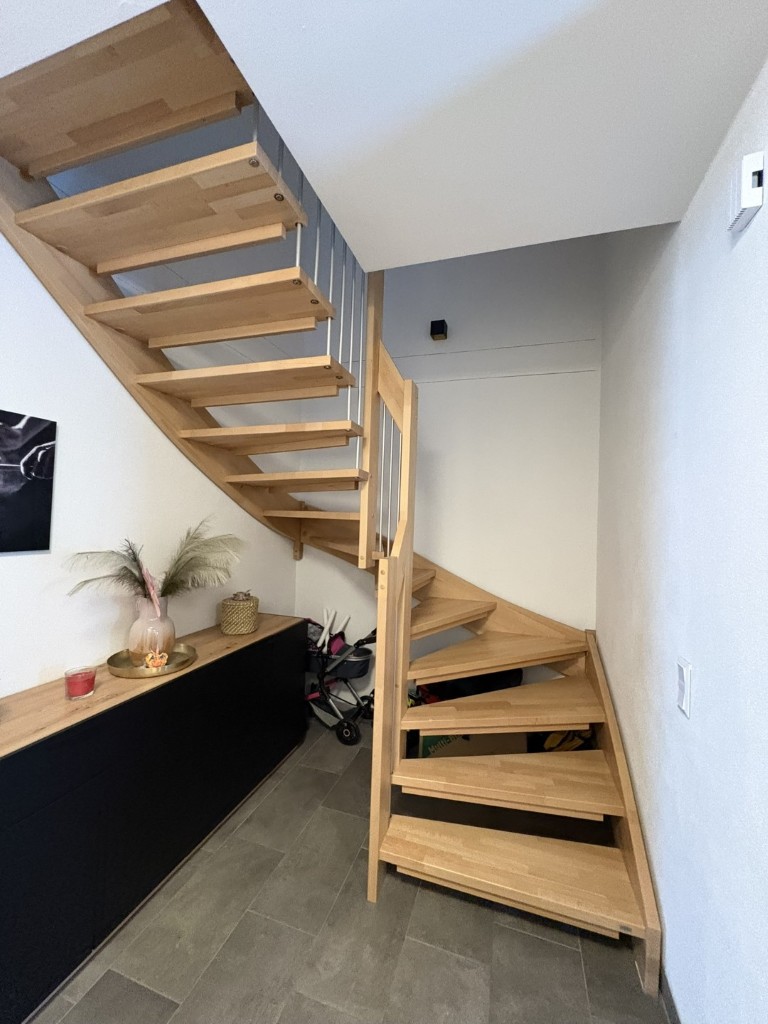 Holztreppe mit Stufen aus hellem Holz und Metallgeländer in einem modernen Wohnhaus