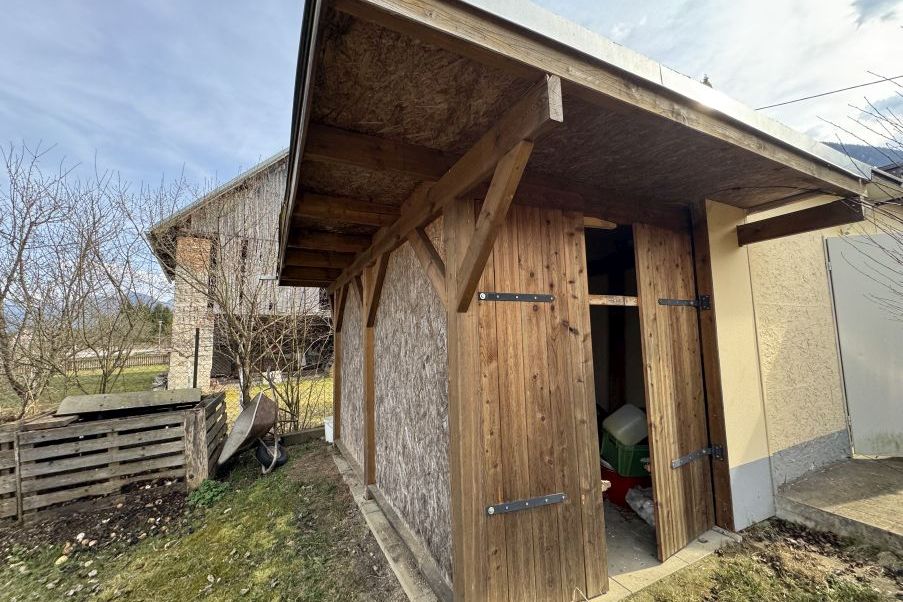 Holzschuppen mit Holztüren und Kompostbehälter im Garten in Österreich