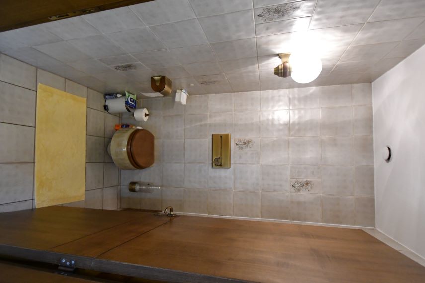 Badezimmer mit WC, gelbem Handtuch und Holztisch