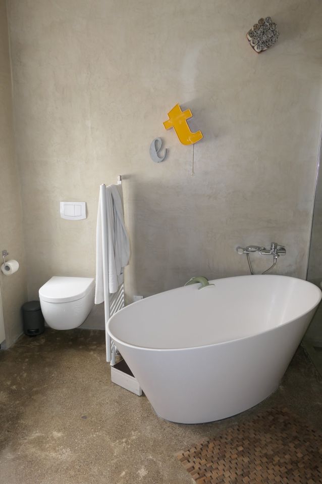 Badezimmer mit freistehender Wanne, Toilette und Heizkörper mit Handtuch