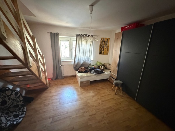 Schlafzimmer mit Bett, Kleiderschrank, Treppe und Fenster