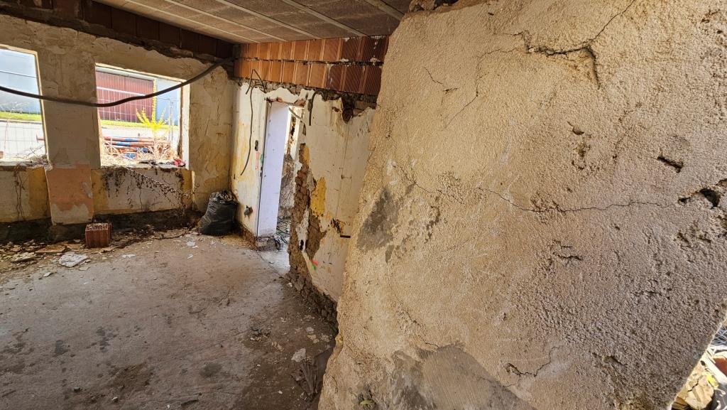 Abrissarbeiten in einem Haus mit freiliegenden Ziegeln und Rissen in der Wand