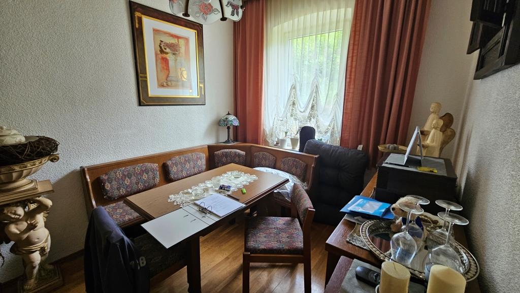 Esszimmer mit Sitzbank und Tisch, vor einem Fenster mit Vorhängen