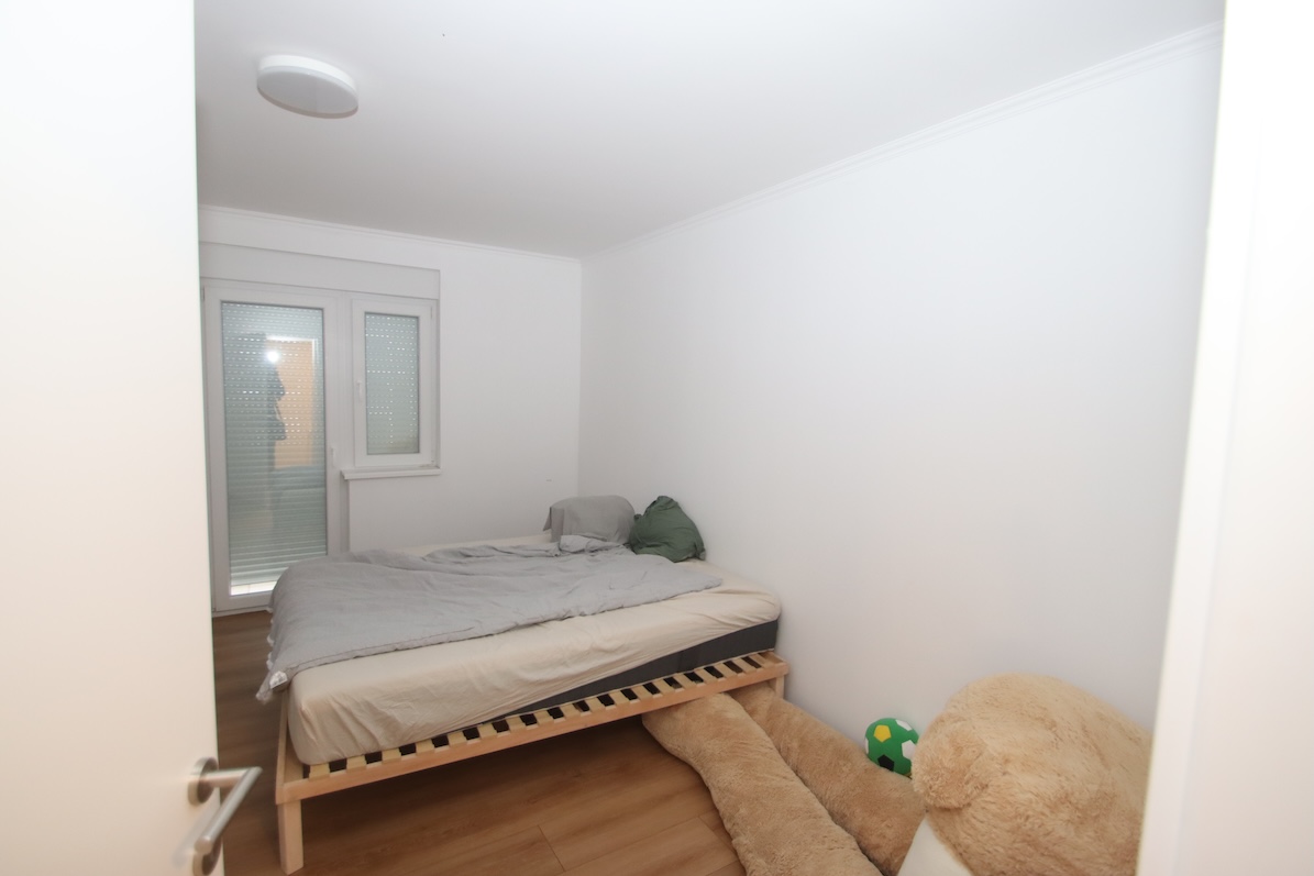 Schlafzimmer mit Bett, Fenster und Spielzeug im Raum.