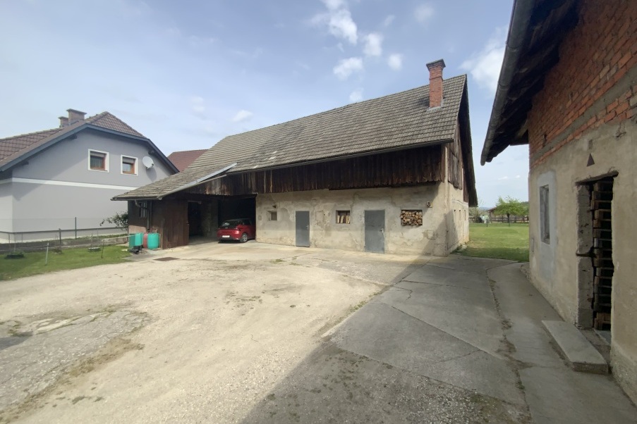 Bauernhaus mit rotem Auto in der Garage und Nachbarhaus in ländlicher Umgebung