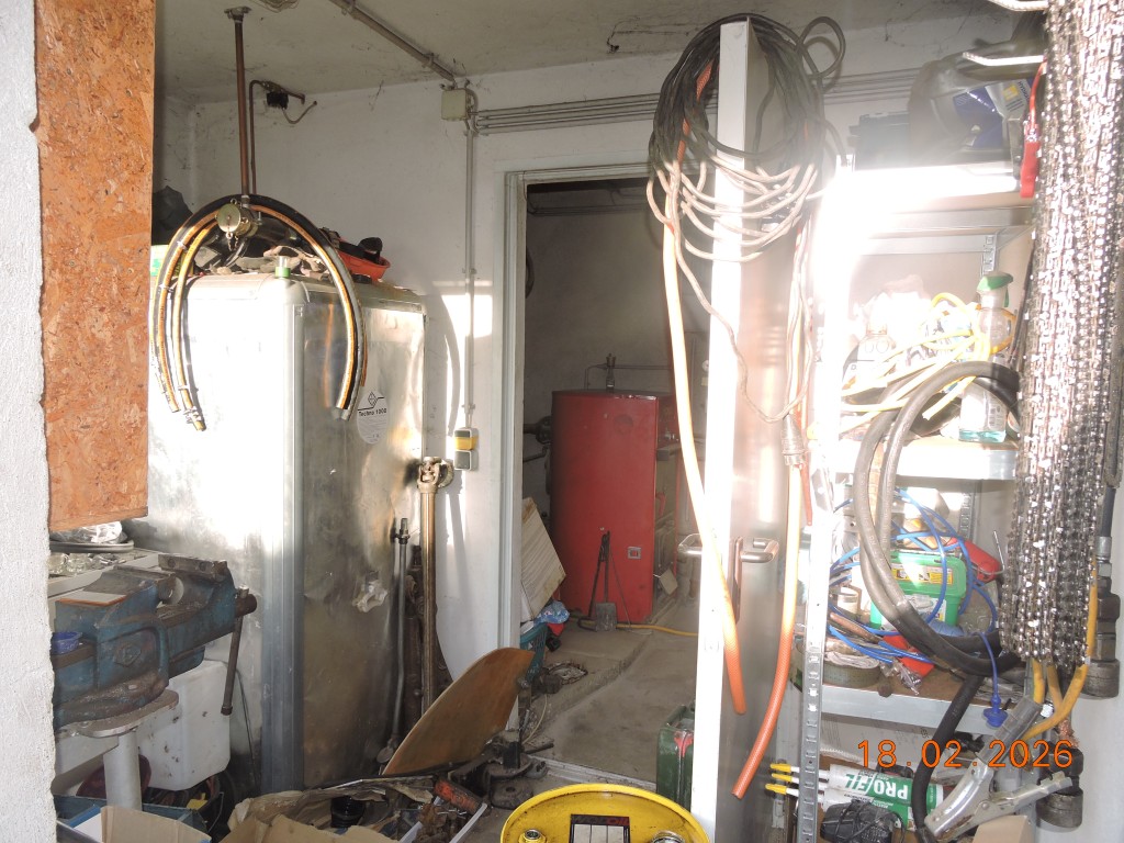 Werkstatt mit Boilertank, Werkbank und Regal mit Kabeln