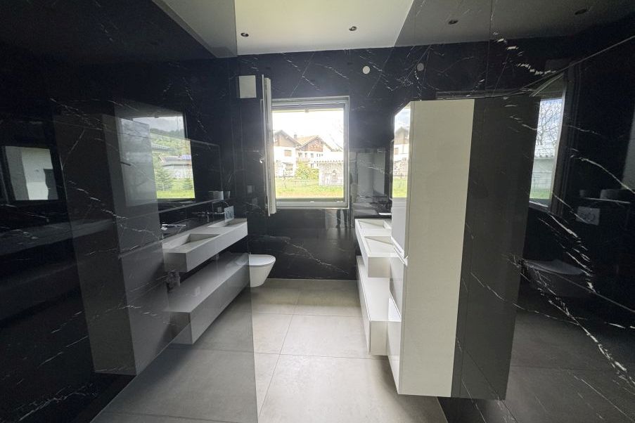Badezimmer mit schwarzen Marmorfliesen, Doppelwaschbecken und Toilette