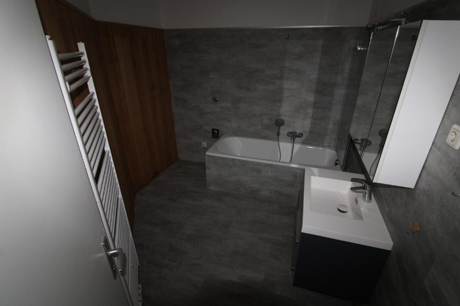 Badezimmer mit Wanne, Waschbecken und Holzakzentwand