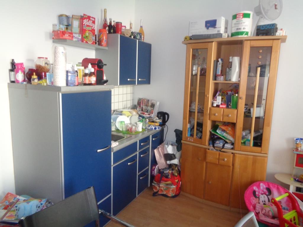 Küchenzeile mit blau-silbernen Schränken und einem Holzschrank gefüllt mit Haushaltswaren