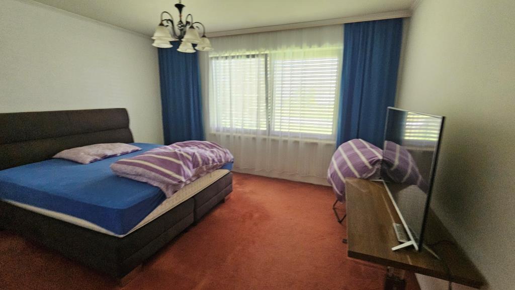 Schlafzimmer mit Doppelbett, orangefarbenem Teppich und Fernsehgerät